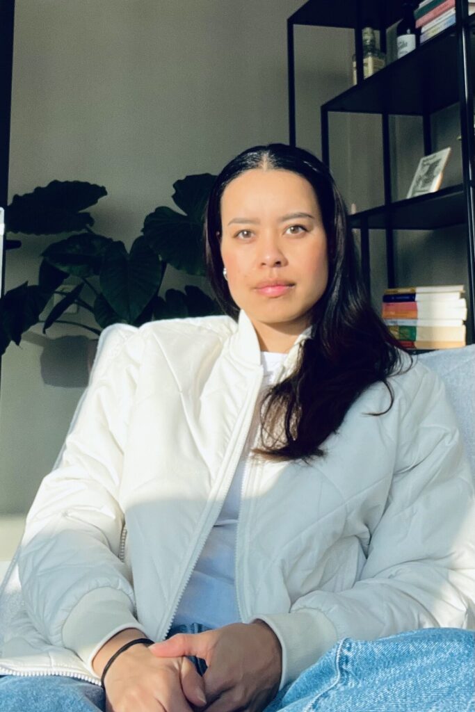 Vrouwencoach zittend in moderne lounge stoel – minimalistische setting in wit, beige en zwart